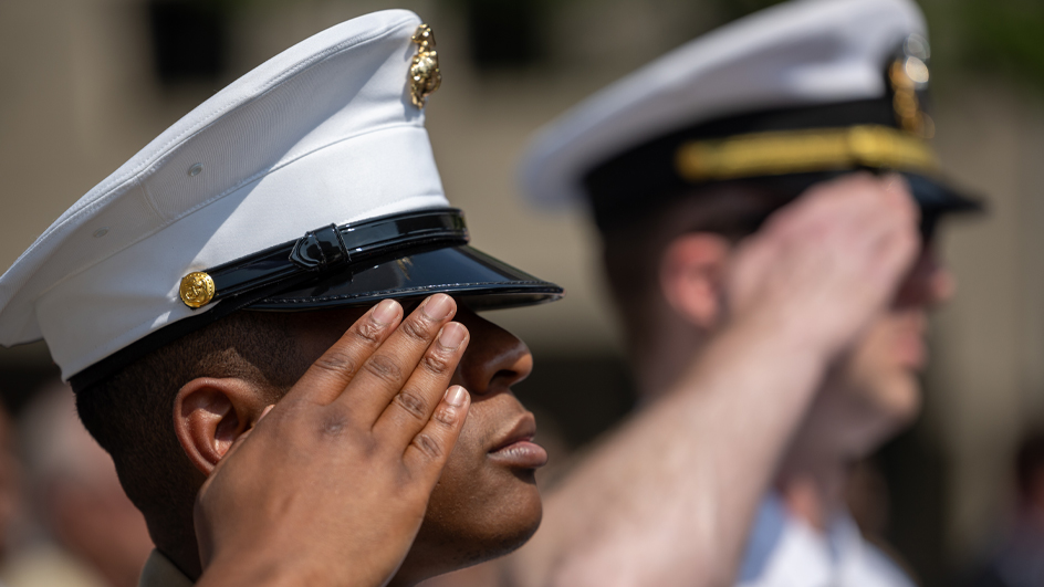 A tight shot of two men in naval uniforms saluting
