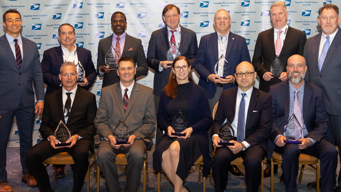 People sit in rows of chairs and hold plaques