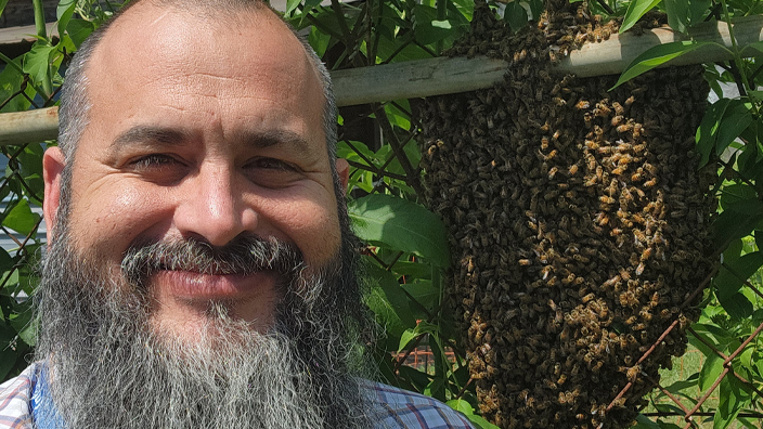 A man stands next to a beehive