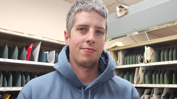 A man stands in a Post Office workroom