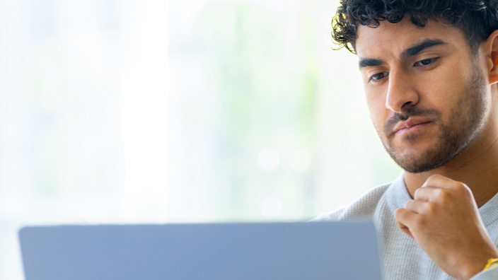 A man sits in front of a computer monitor in an office environment