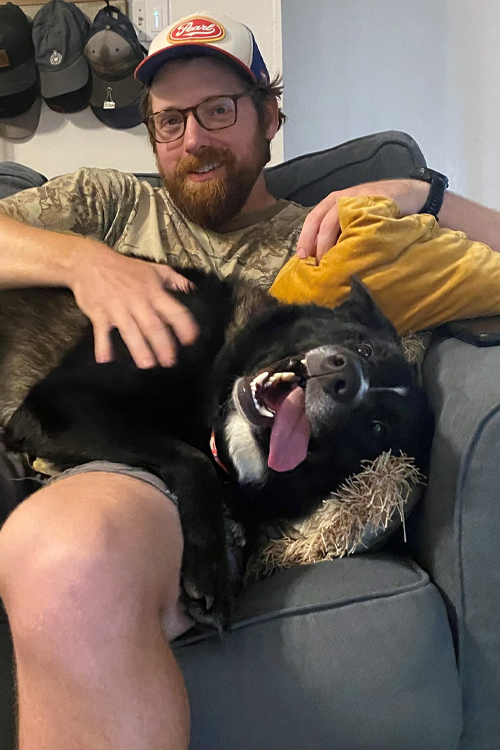 A man sits on a sofa with a dog on his lap
