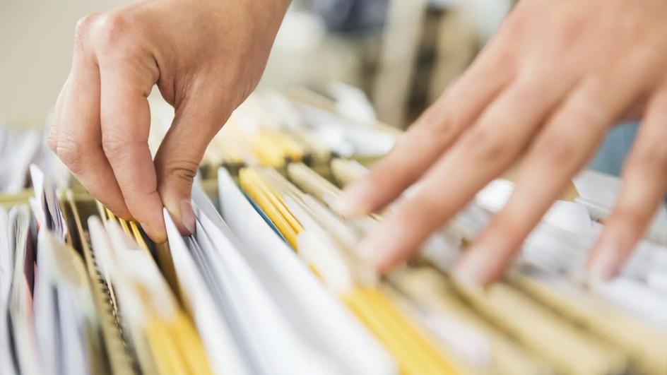 Hands look through files in a cabinet