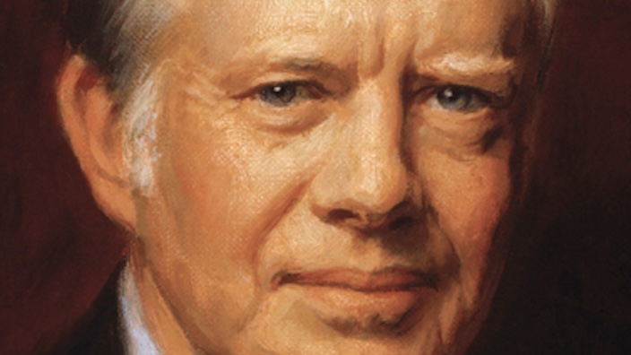 A stamp featuring an oil painting of Jimmy Carter wearing suit and tie