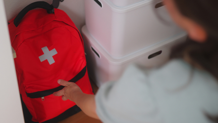 A red duffel bag with an emergency logo is stored in a closet