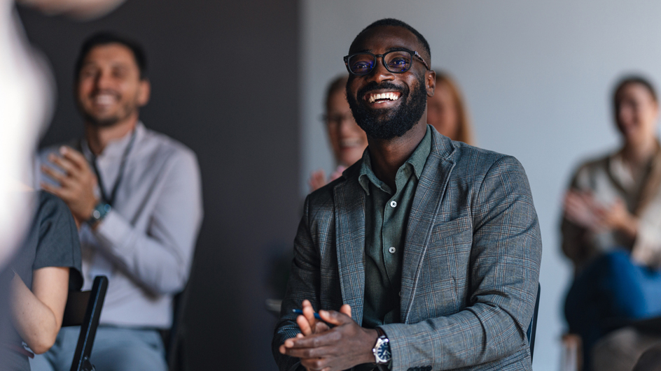 A group of adult students listen to an unseen teacher in a classroom setting