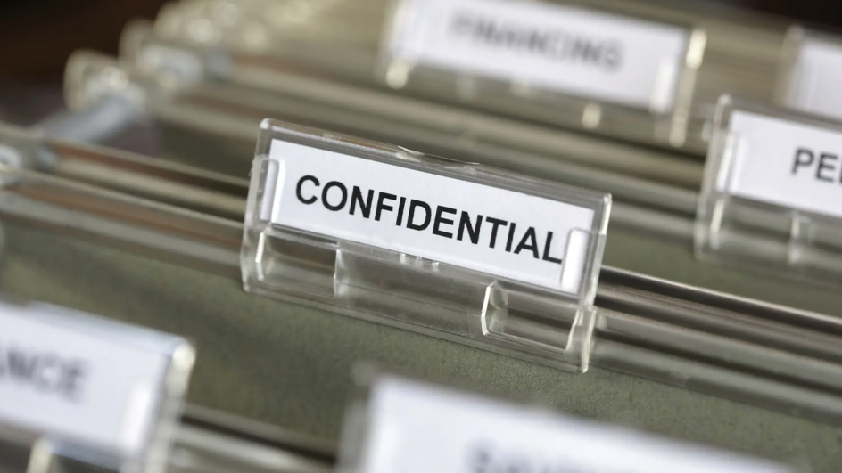 A file cabinet drawer that is open, showing files that are marked confidential