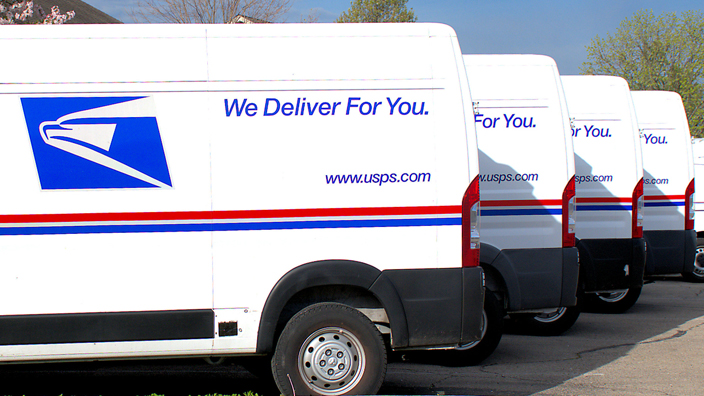 A lineup of USPS-branded vans in a parking lot