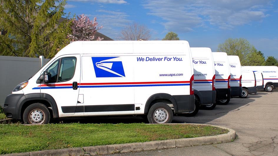 A lineup of USPS-branded vans in a parking lot