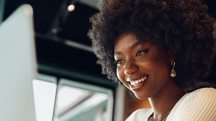 A smiling woman sits at a computer.
