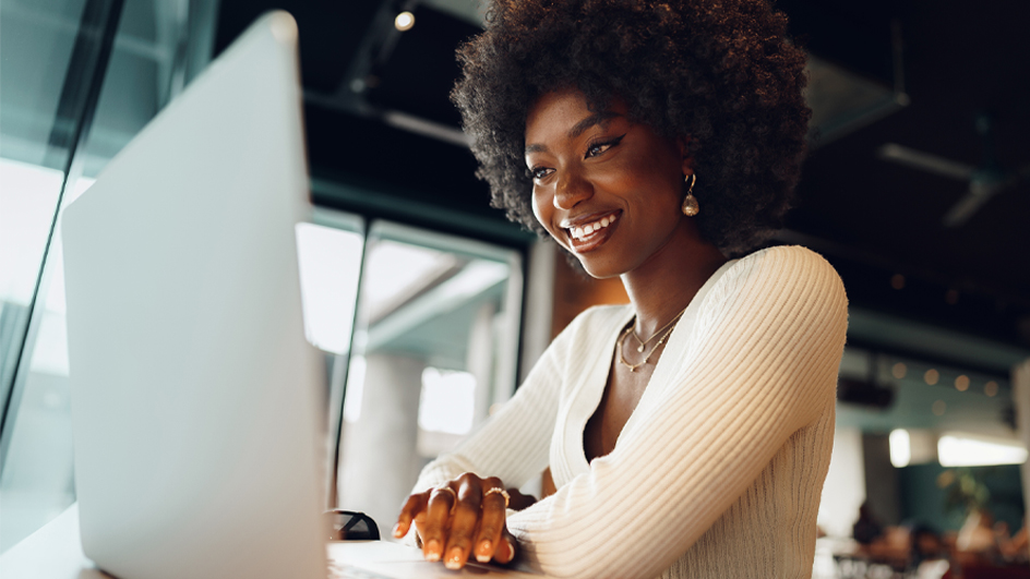 A smiling woman sits at a computer.