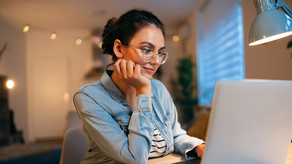 A woman smiles as she sits in front of a computer monitor