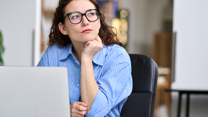 A woman sits at a desk with a skeptical expression