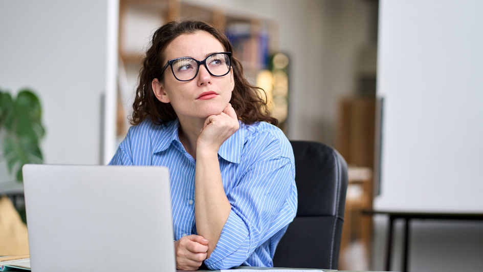 A woman sits at a desk with a skeptical expression