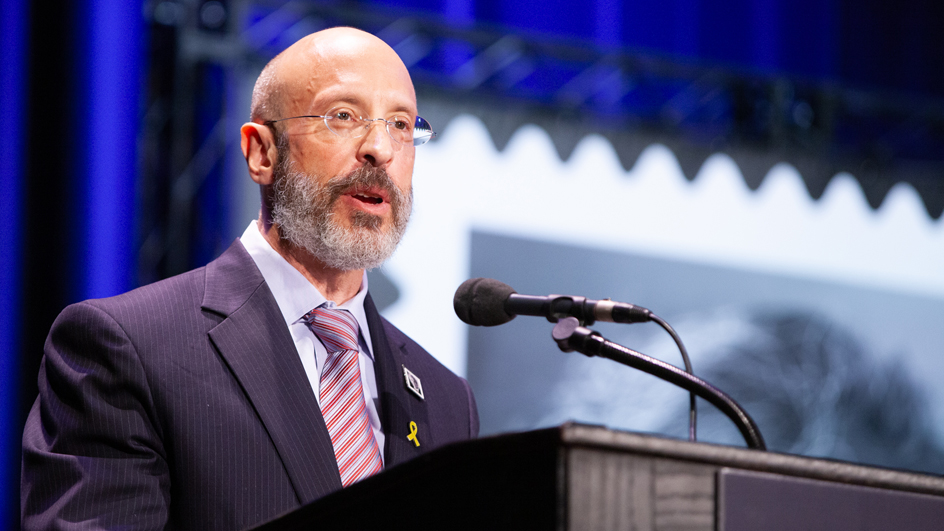 A man stands at a lectern and speaks