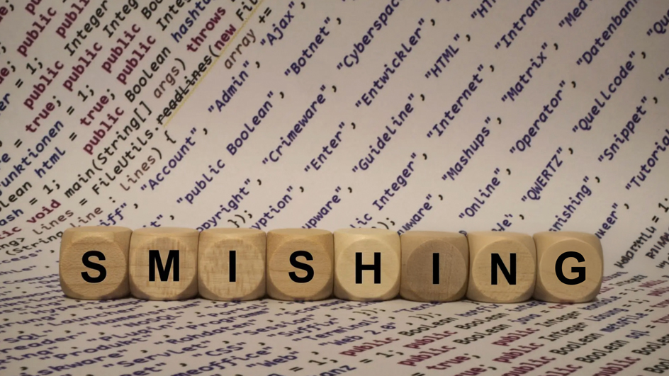 The word “smishing” spelled out in block letters against a backdrop of computer code on paper