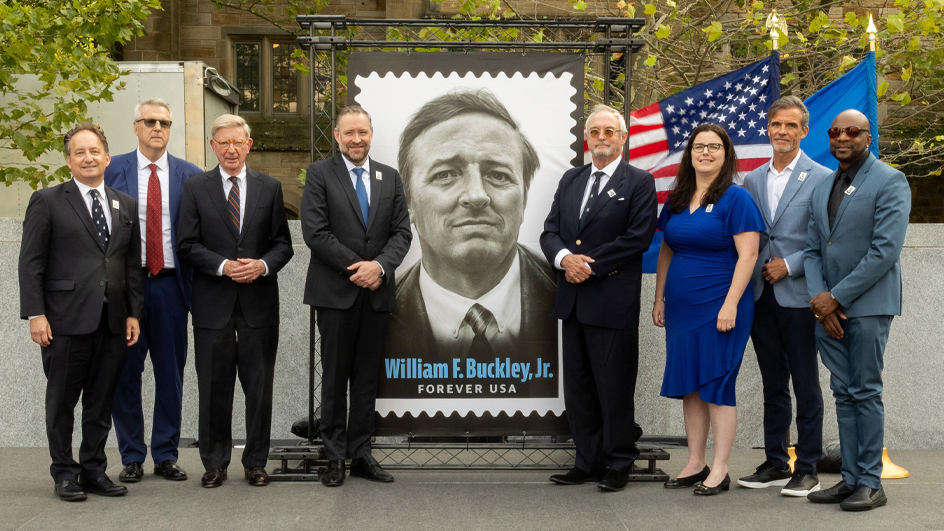 People stand near a poster depicting the William F. Buckley Jr. stamp