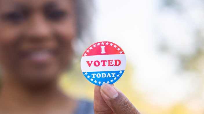 A woman holds up an “I Voted Today” sticker