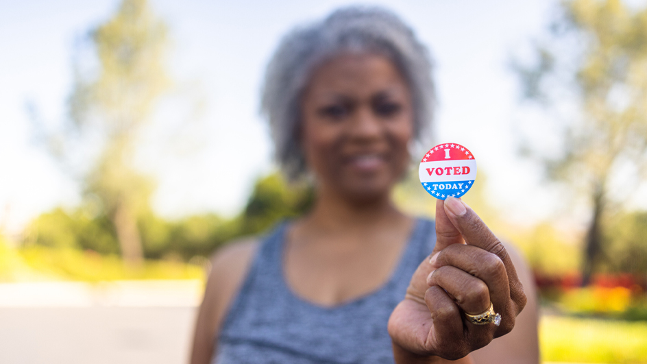 A woman holds up an “I Voted Today” sticker