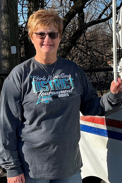 A smiling woman stands next to a Postal Service delivery vehicle
