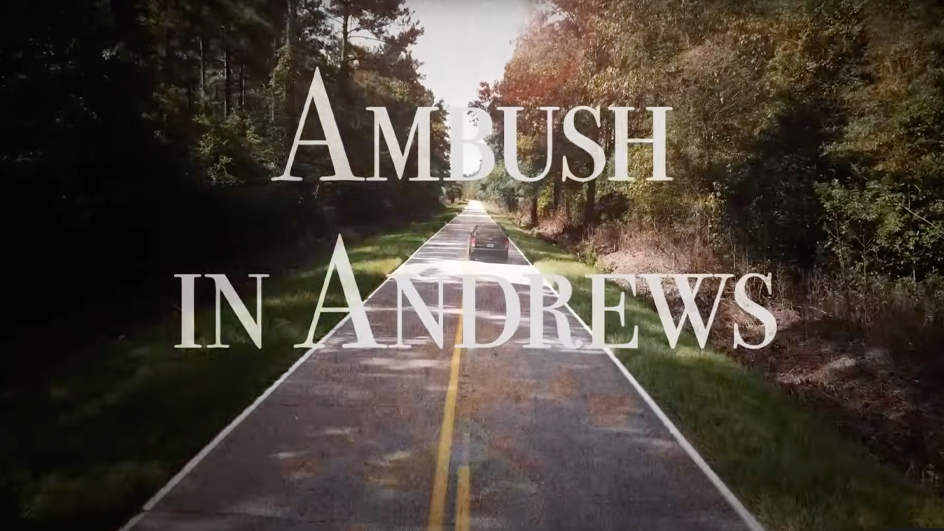 A screenshot from a documentary that shows the title “Ambush in Andrews” over a scene of a car traveling along a tree-lined rural road