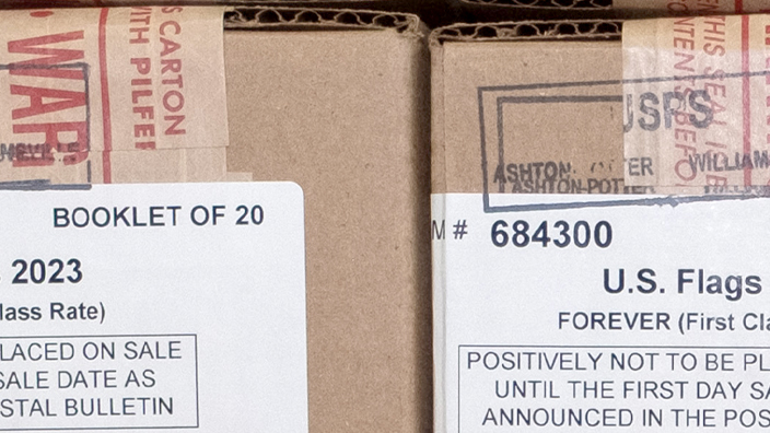 Boxes labeled as U.S. Flag stamps are stacked on top of each other in several rows