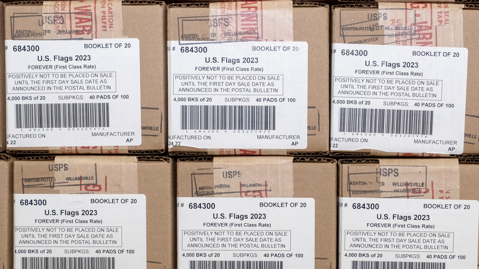 Boxes labeled as U.S. Flag stamps are stacked on top of each other in several rows