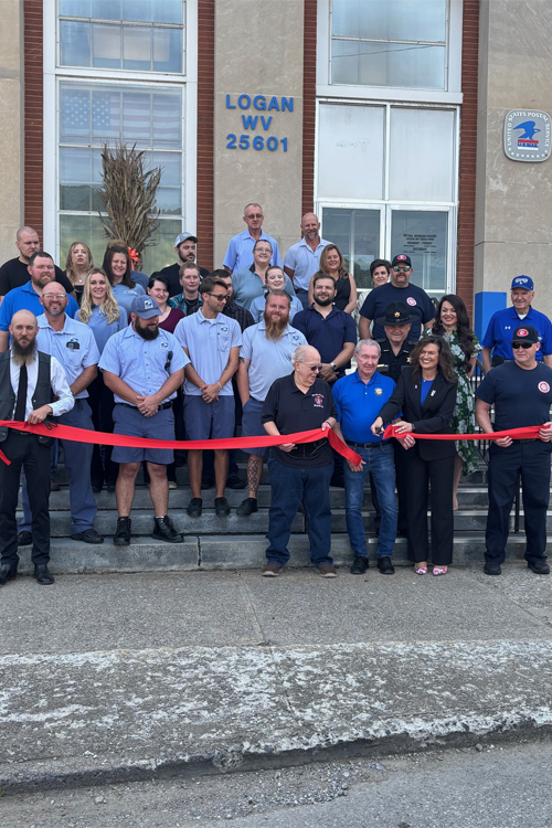 People stand in front of a Post Office holding a ceremonial ribbon