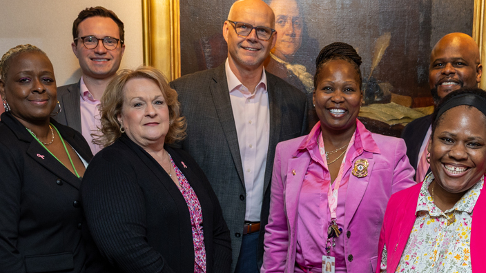 A group of people, many wearing pink clothing, stand together