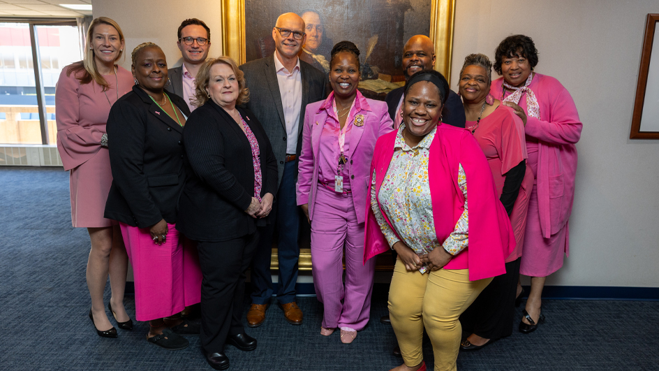 A group of people, many wearing pink clothing, stand together