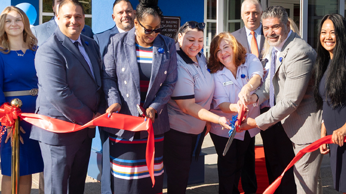 People cut a ceremonial ribbon outside a modern postal facility