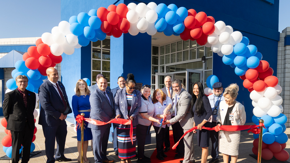 People cut a ceremonial ribbon outside a modern postal facility