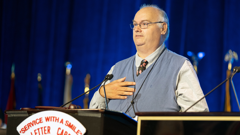 A man stands at a lectern and speaks