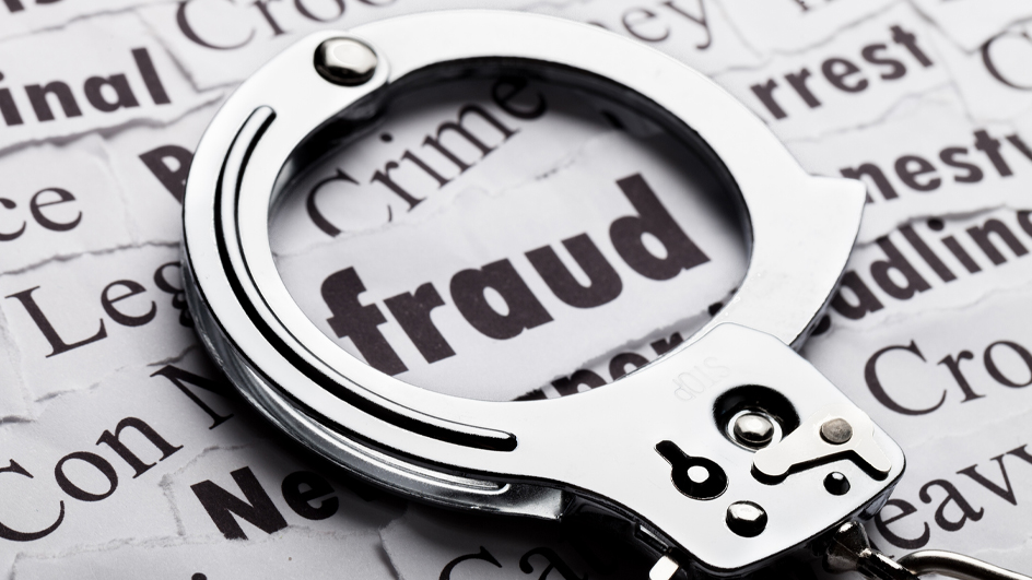 A pair of handcuffs laying on papers, with the word “fraud” visible through the center of the cuffs
