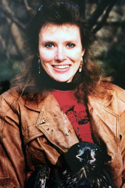 A woman sits with an owl on her lap