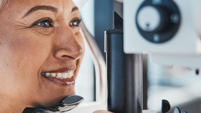 A woman sits in an eye doctor’s office as her eyes are examined