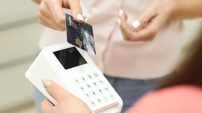 A woman at a medical reception desk takes a credit card from a patient