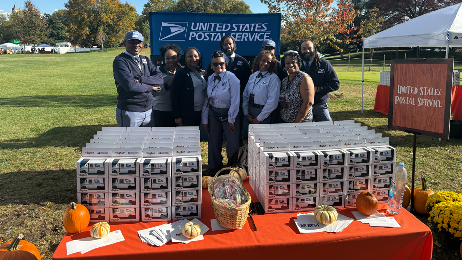 A group of uniformed postal employees smiling on the White House lawn