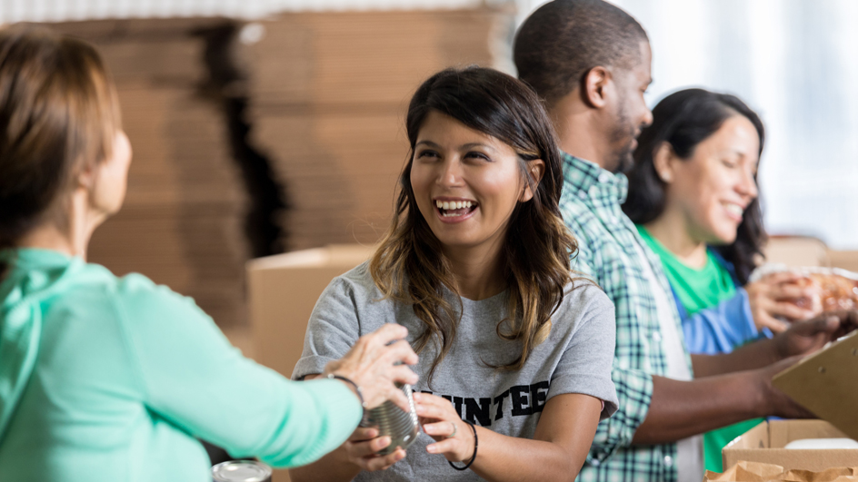 Smiling people collect donations during a food drive.