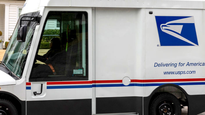 A postal delivery vehicle parked on a suburban street