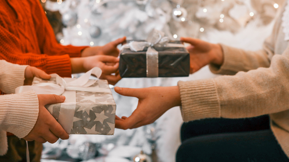 Multiple people exchanging gifts in front of a Christmas tree