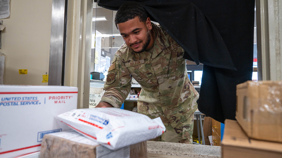 A young man in military garb handles USPS-branded packages