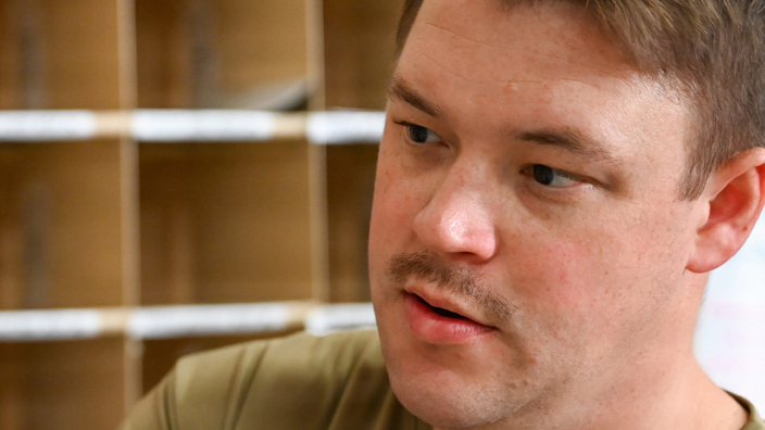 A young man in a military uniform examines a letter