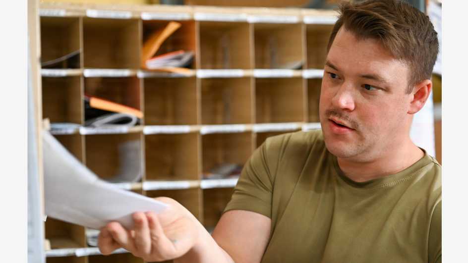A young man in a military uniform examines a letter