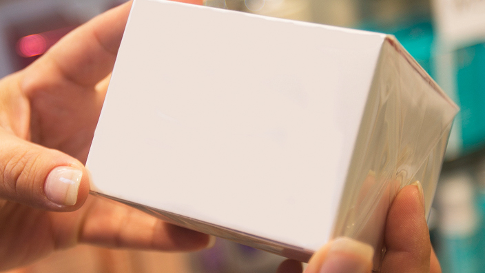 A white box containing perfume, wrapped in plastic