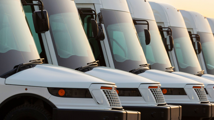 A tight shot of the front end of shiny new postal vehicles lined up next to each other on a parking lot