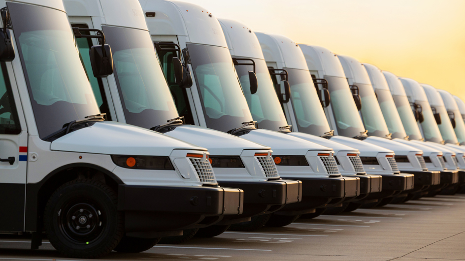 A tight shot of the front end of shiny new postal vehicles lined up next to each other on a parking lot