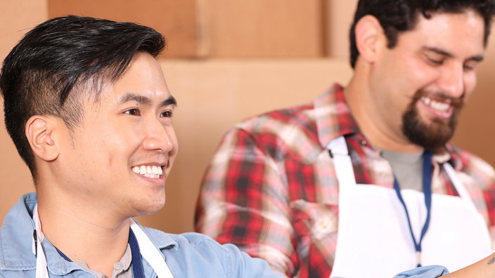 A man smiles and wields a ladle in a soup kitchen
