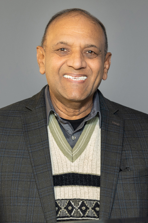 A man smiles while standing at a lectern