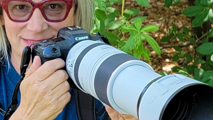 A woman peers over a camera